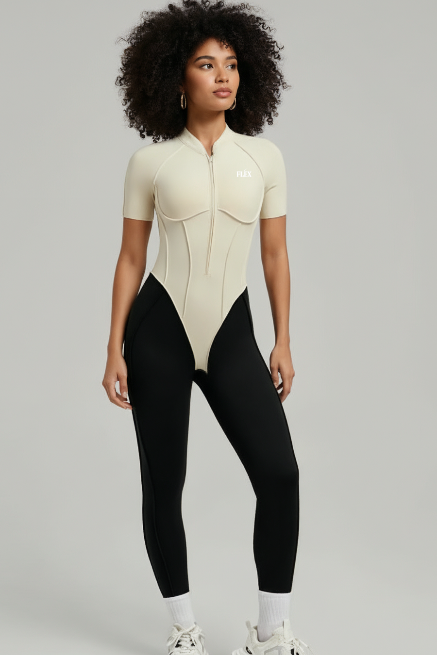 Woman wearing a beige bodysuit and black leggings on a gray background