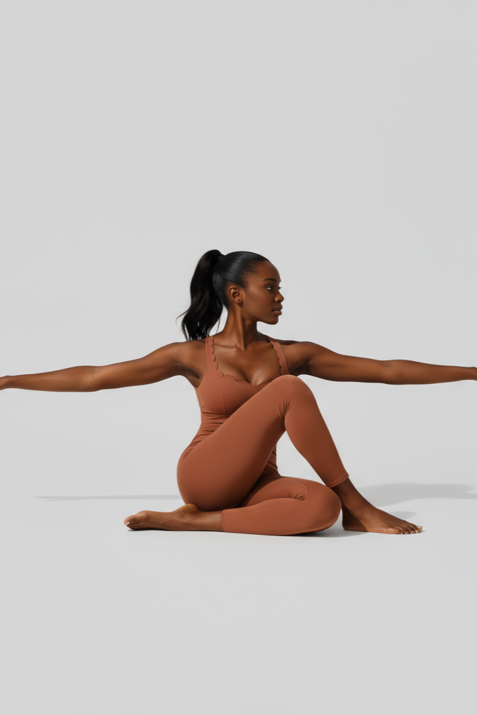 Person wearing a brown bodysuit sitting with arms outstretched on a light gray background